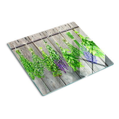 Glass chopping board Dried herbs on a wood background