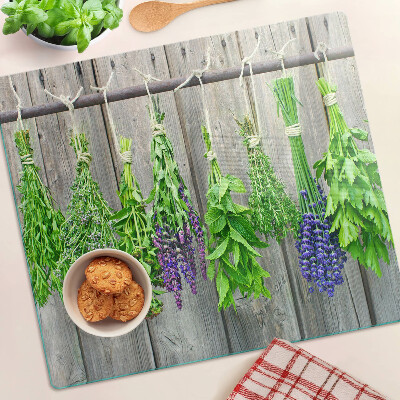 Glass chopping board Dried herbs on a wood background