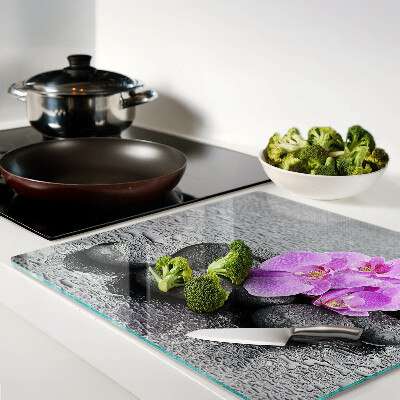 Glass chopping board Flowers and stones against the water