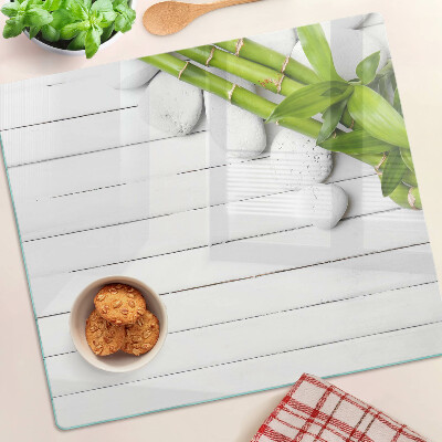 Glass kitchen board Bamboo and stones on a wood background
