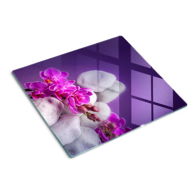 Glass chopping board Orchid flowers on a background of stones