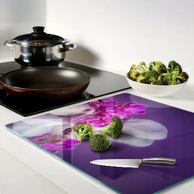 Glass chopping board Orchid flowers on a background of stones