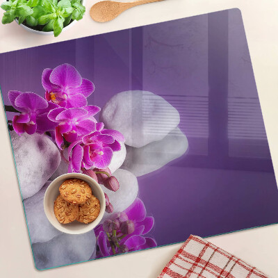 Glass chopping board Orchid flowers on a background of stones