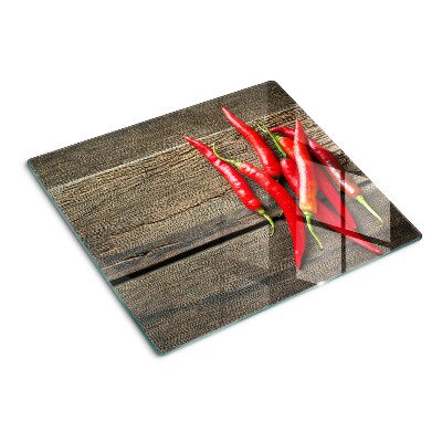 Glass chopping board Chili peppers on a wooden background