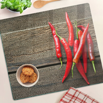 Glass chopping board Chili peppers on a wooden background