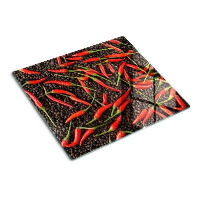 Glass chopping board Chili peppers on black pepper