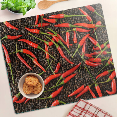 Glass chopping board Chili peppers on black pepper