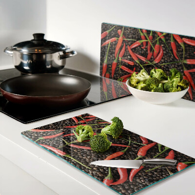 Glass chopping board Chili peppers on black pepper