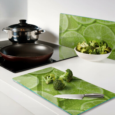 Glass chopping board Lime slices on a green background