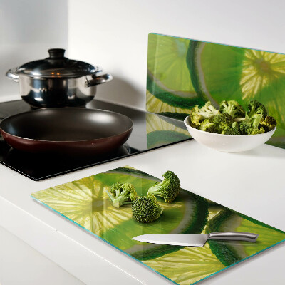 Glass kitchen board Lime slices on a green background