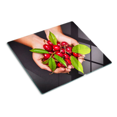 Glass chopping board Red cherries in hands