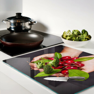Glass chopping board Red cherries in hands