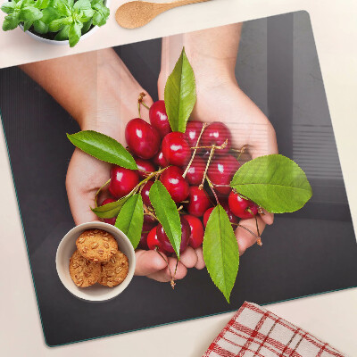 Glass chopping board Red cherries in hands