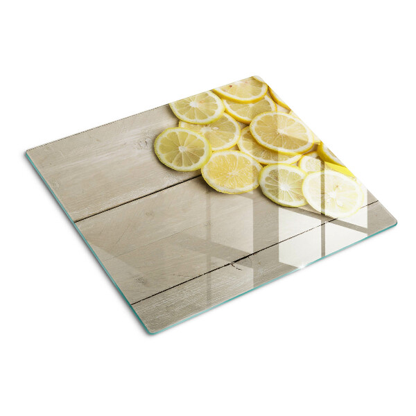 Glass chopping board Lemon slices on a wooden background