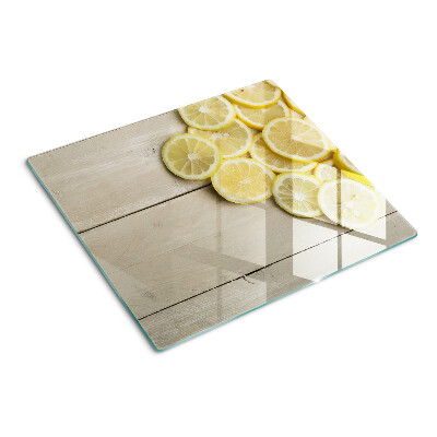 Glass chopping board Lemon slices on a wooden background