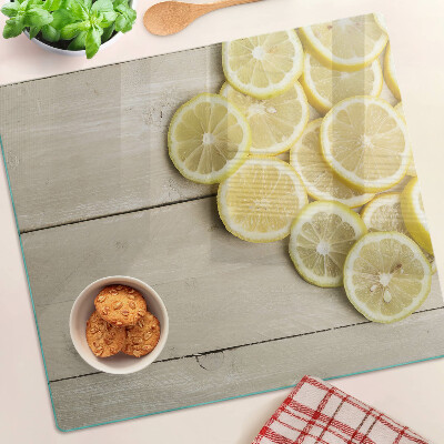 Glass chopping board Lemon slices on a wooden background