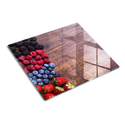 Glass chopping board Forest fruits on a wooden background