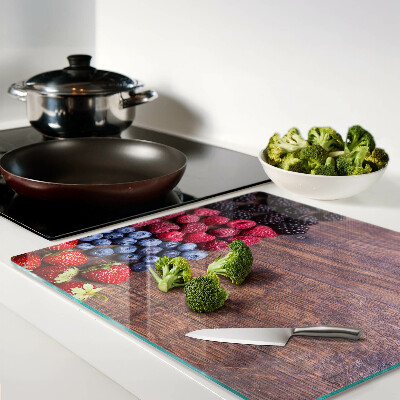Glass chopping board Forest fruits on a wooden background
