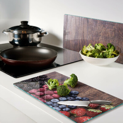 Glass chopping board Forest fruits on a wooden background
