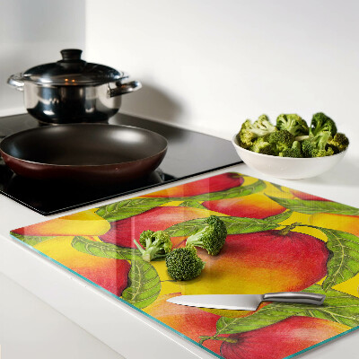 Glass chopping board Peppers on a background of green leaves