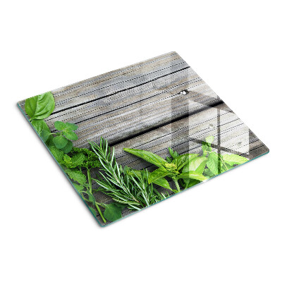 Glass chopping board Green herbs on wooden background