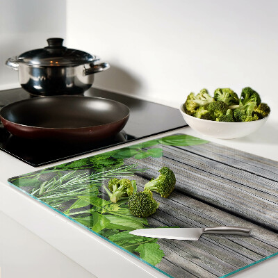Glass chopping board Green herbs on wooden background