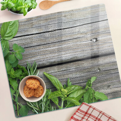 Glass chopping board Green herbs on wooden background