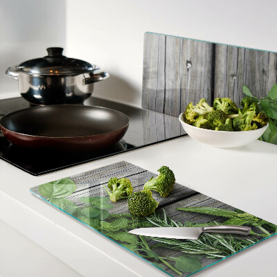 Glass chopping board Green herbs on wooden background