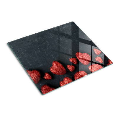 Glass kitchen board Red hearts on a dark background