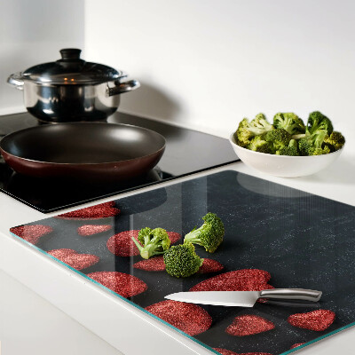 Glass kitchen board Red hearts on a dark background