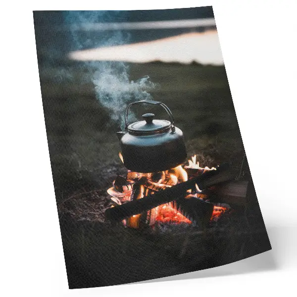 Decorative poster kettle over a fire in the forest by the lake