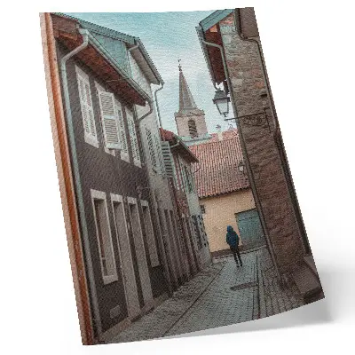 Poster narrow street with tenement houses and a tower with a blue coat