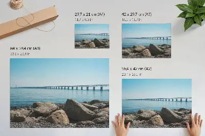Decorative canvas print bridge over blue water with stones on the shore