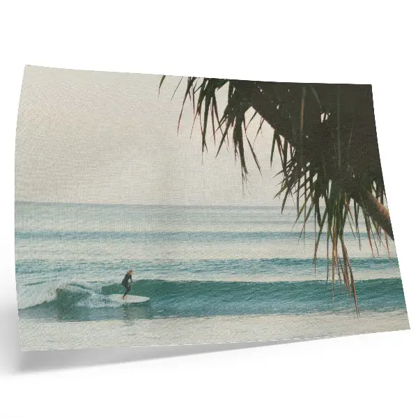 Decorative canvas print featuring a peaceful beach scene with surfing waves and palm trees