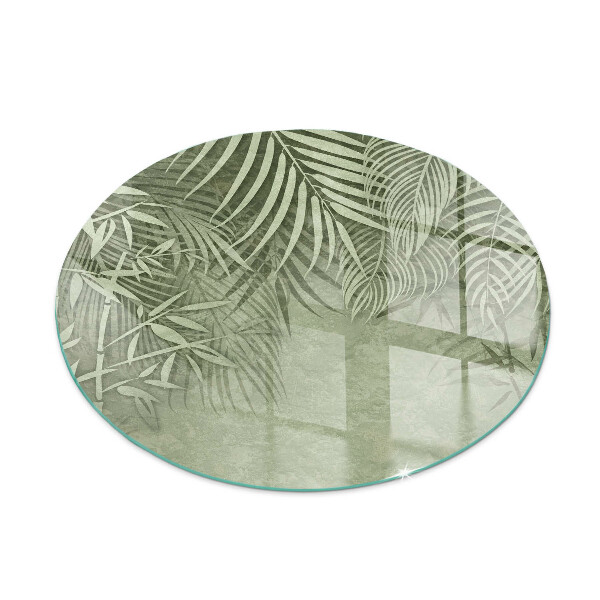 Glass hearth for stove round Tropical leaves in the background