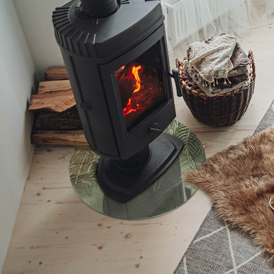 Glass hearth for stove round Tropical leaves in the background