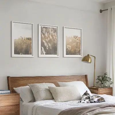 Set of 3 framed landscape wall art pieces featuring grass and flowers with a warm aesthetic